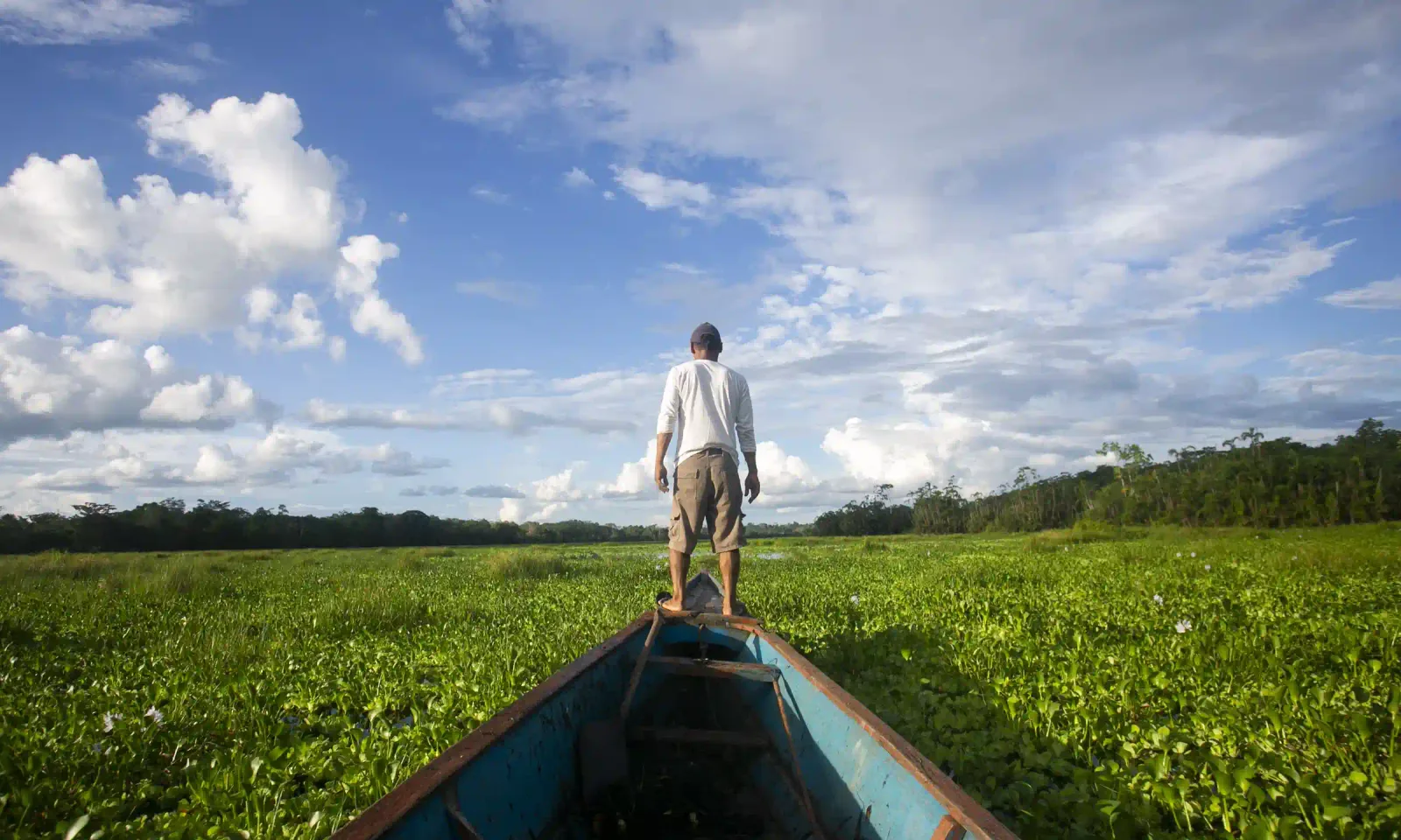 Traveler at the bow of a boat on an Amazon river journey through the jungle