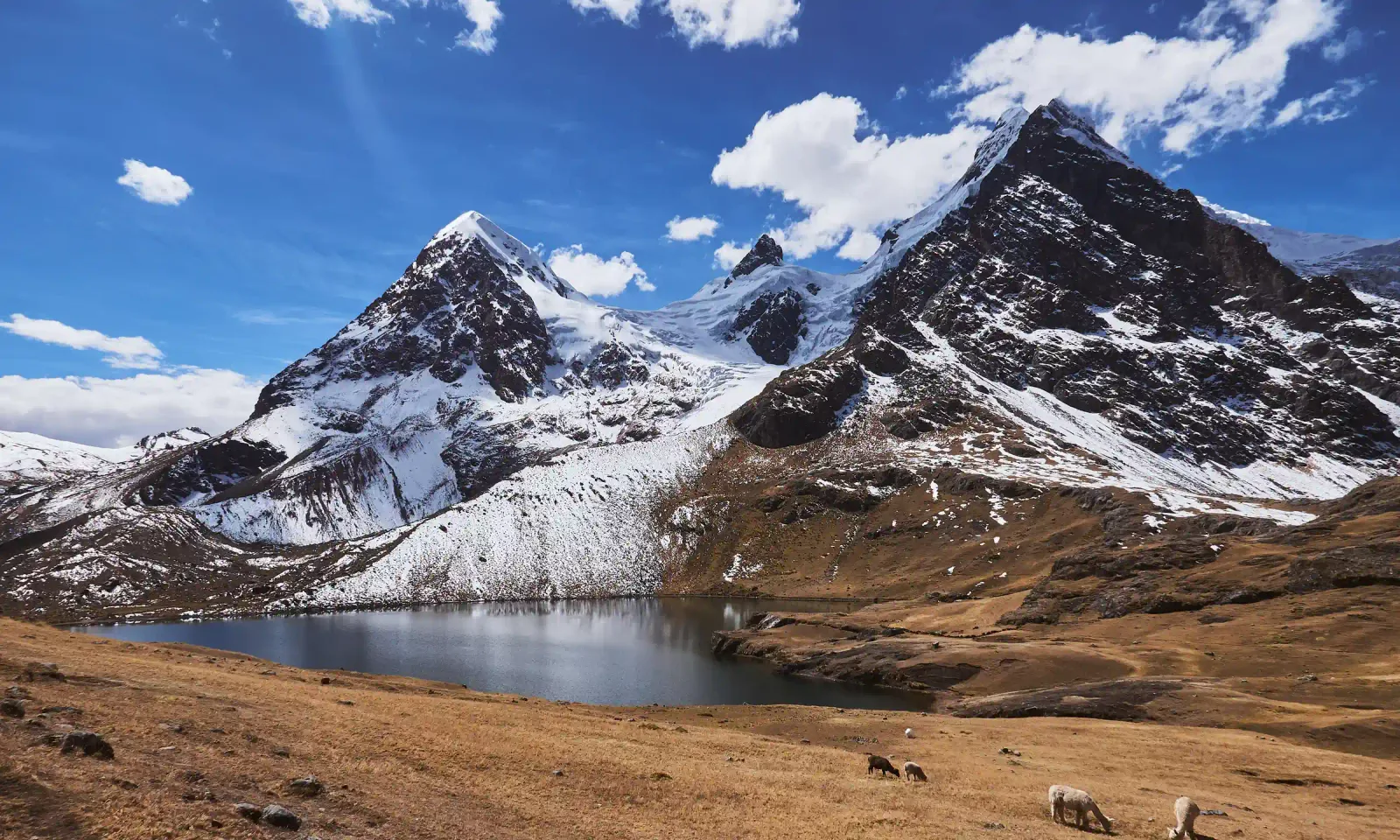 A turquoise glacial lake beneath the snow-capped Ausangate mountain near Cusco