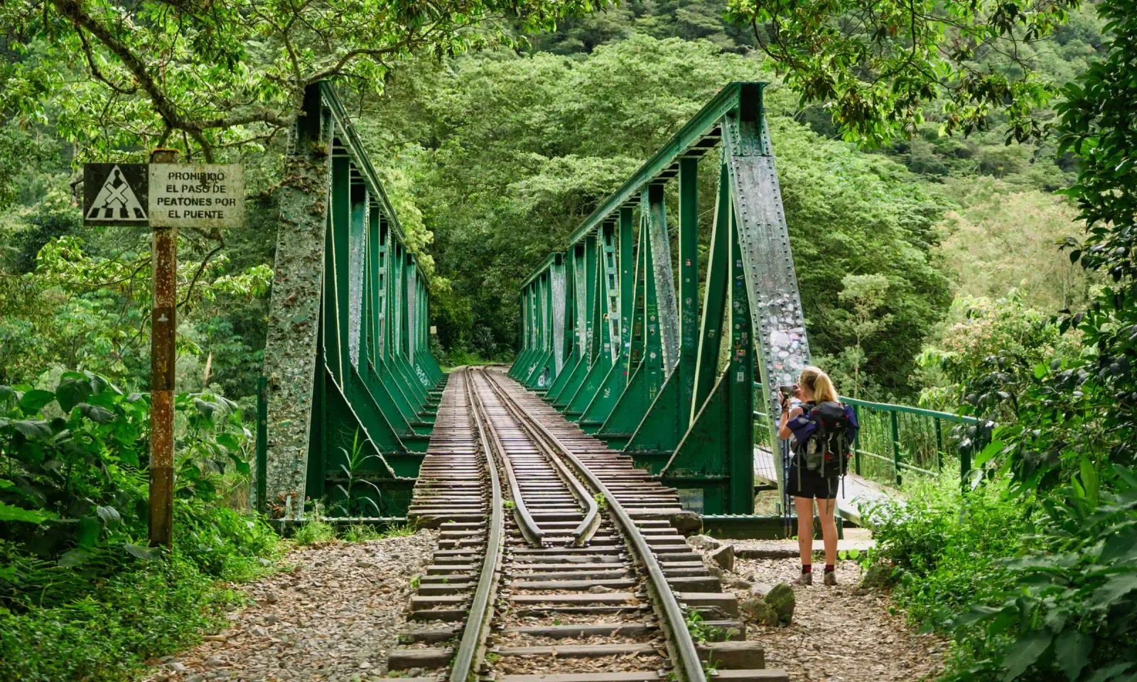 Crossing a jungle railway bridge on the 4-day Inca Jungle Trail to Machu Picchu