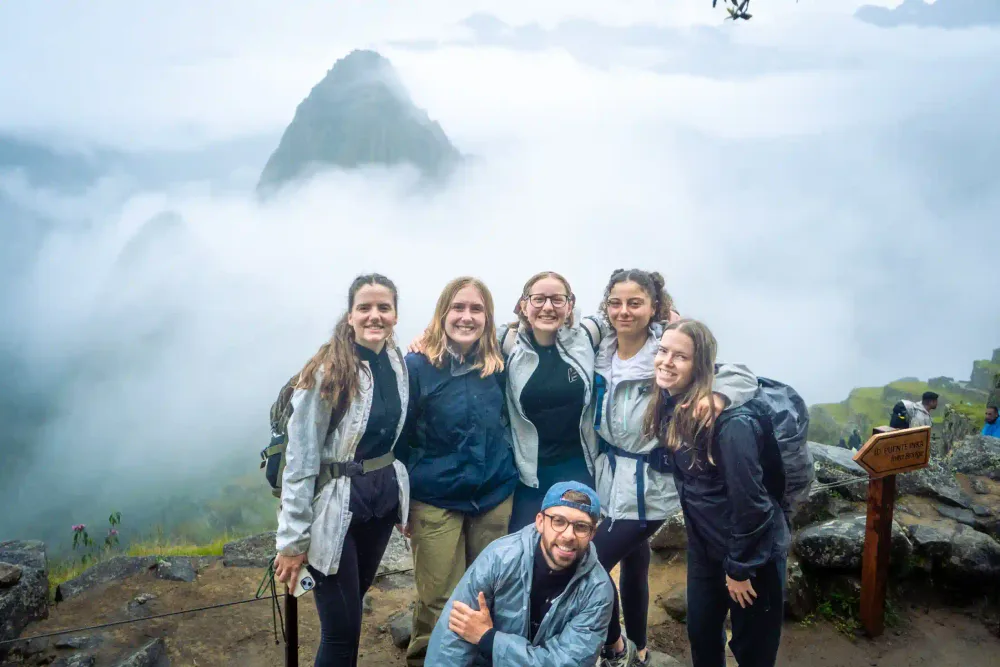 Travelers at the Machu Picchu viewpoint with Huayna Picchu behind