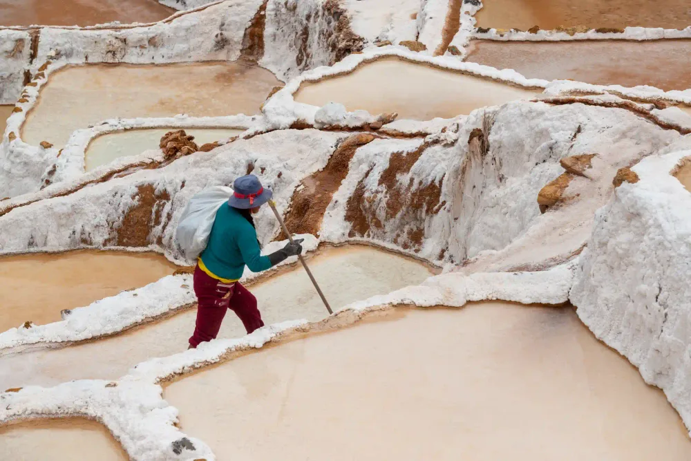 A salt worker harvesting salt by hand at the Maras salt mines