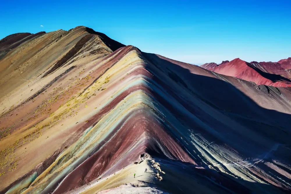 The striped slopes of Vinicunca with hikers showing the scale