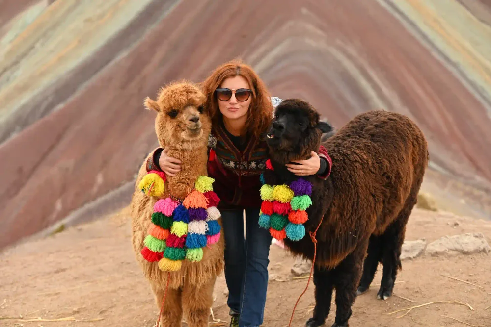 A visitor with two alpacas in front of Rainbow Mountain